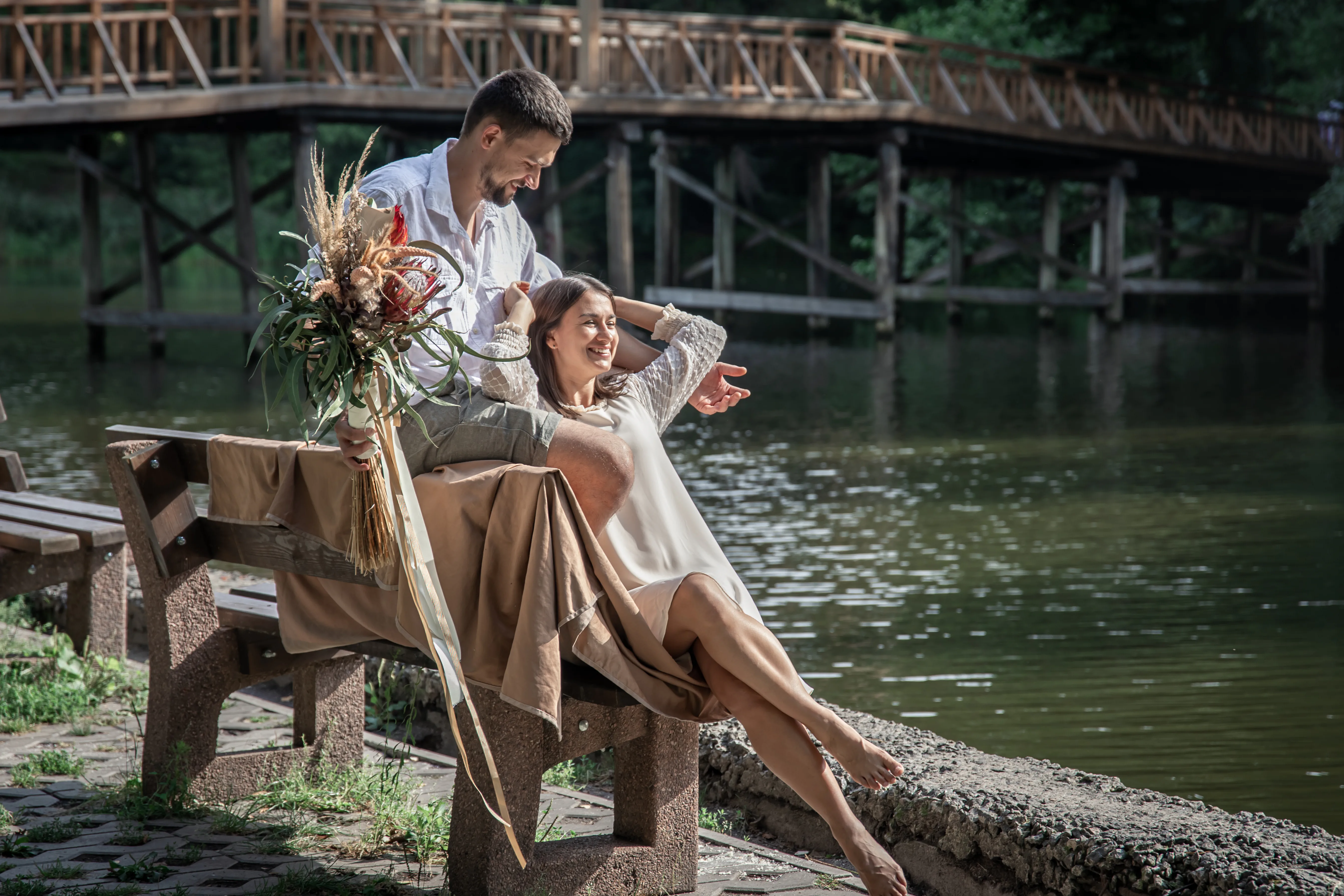 Couple with flowers on a bench by the water
