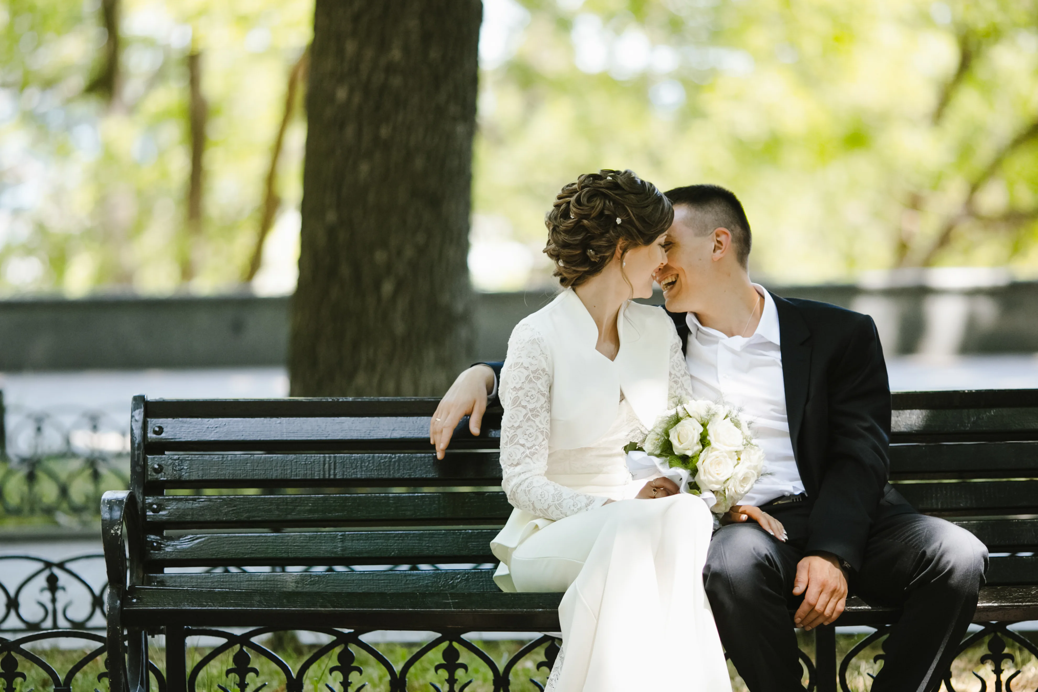 Newlyweds seated on a bench, laughing together