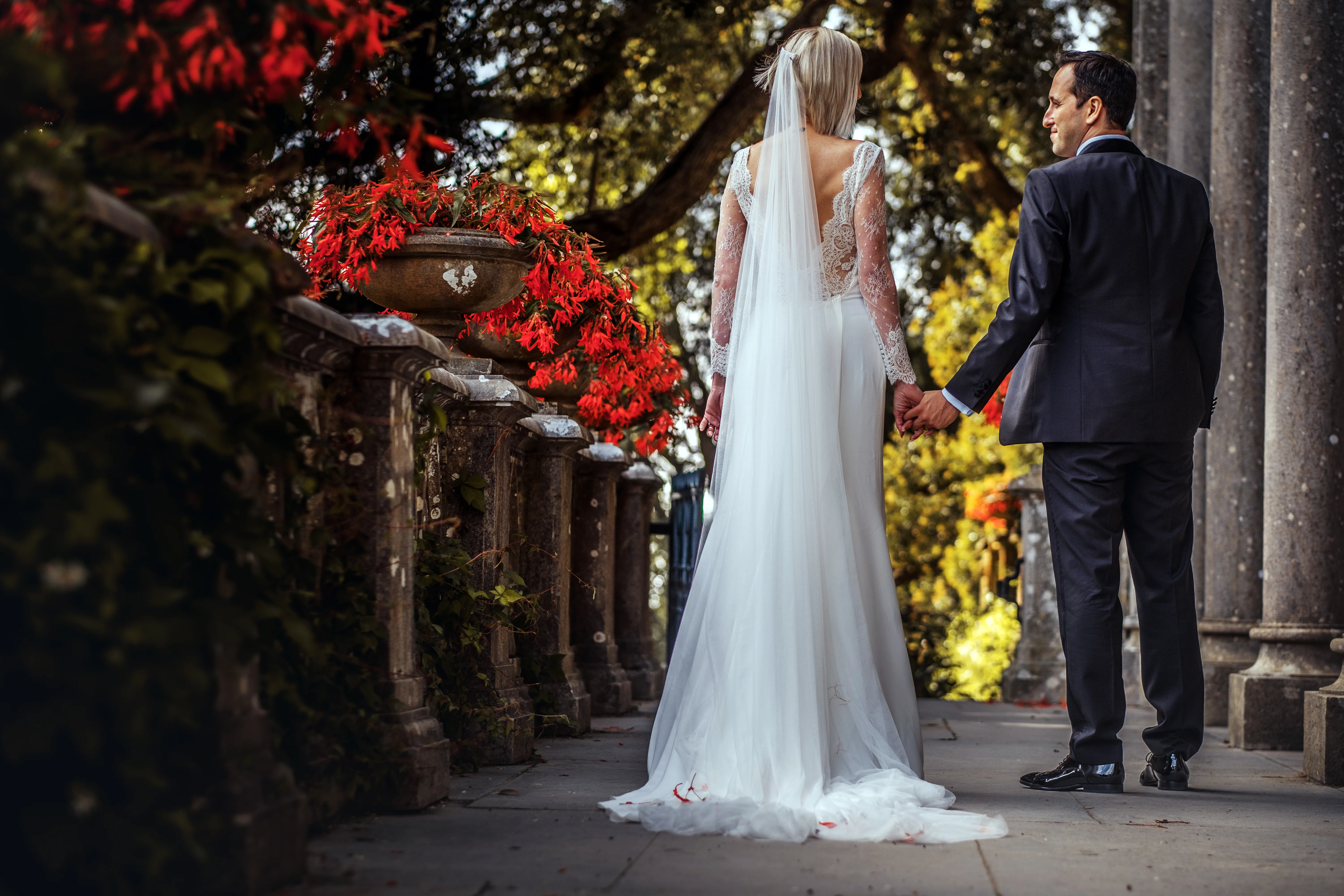 Newlyweds walking through the colonnade of a stone palace